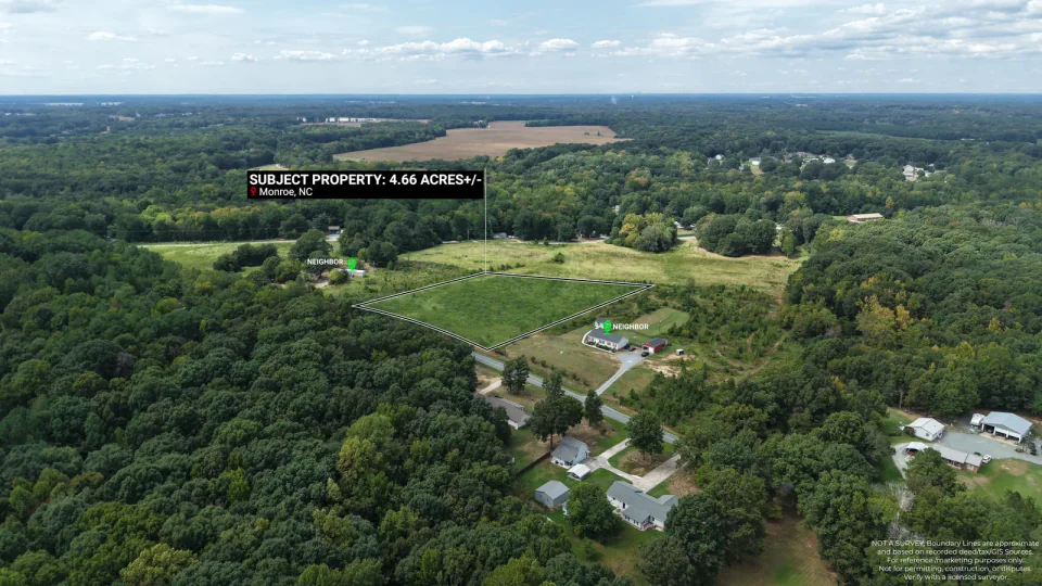 Aerial view of open land and woodland with a property location marker